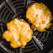 Two air fryer hamburgers covered in melted cheese.