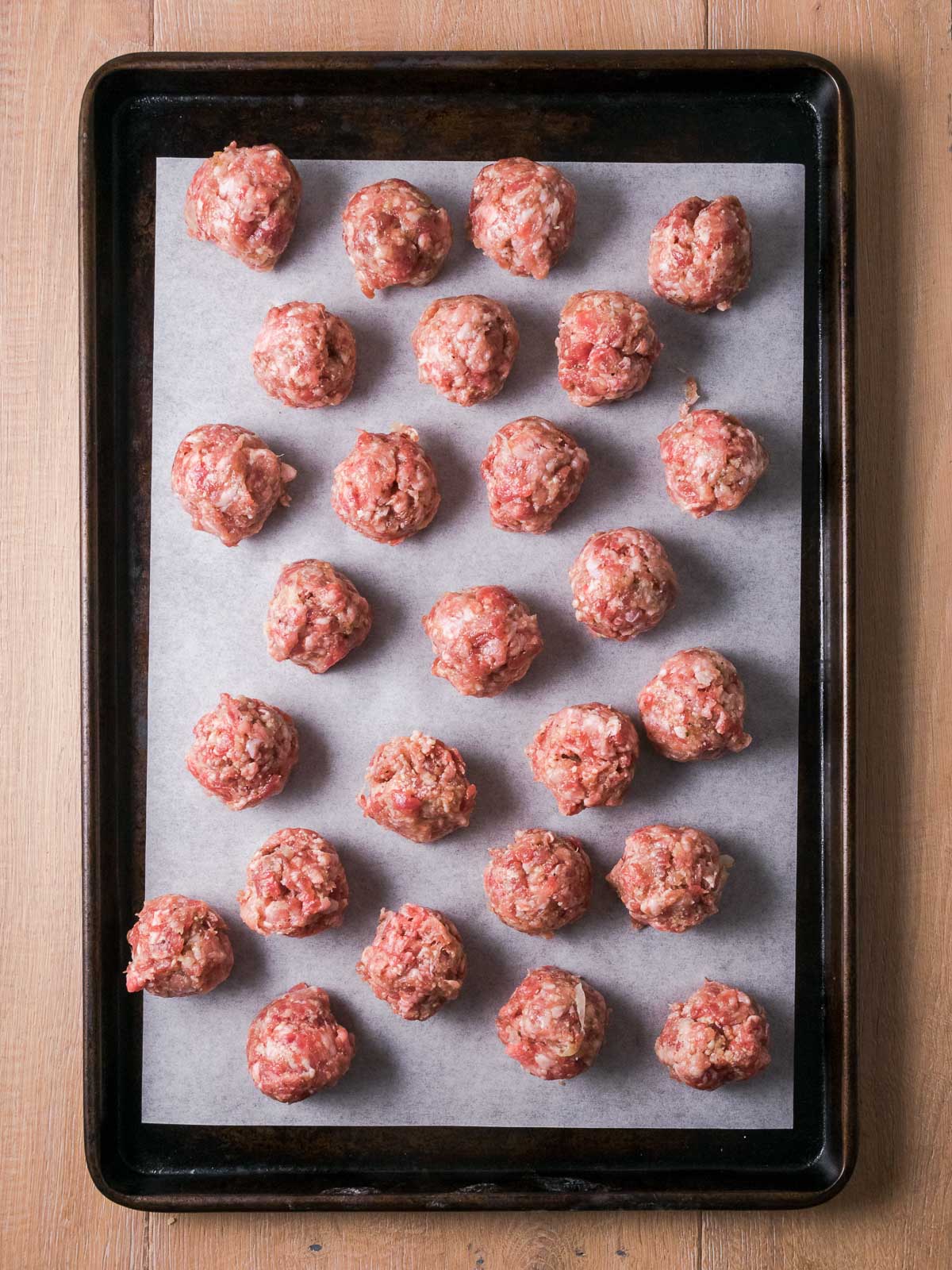 Raw Gluten free meatballs on a baking sheet.