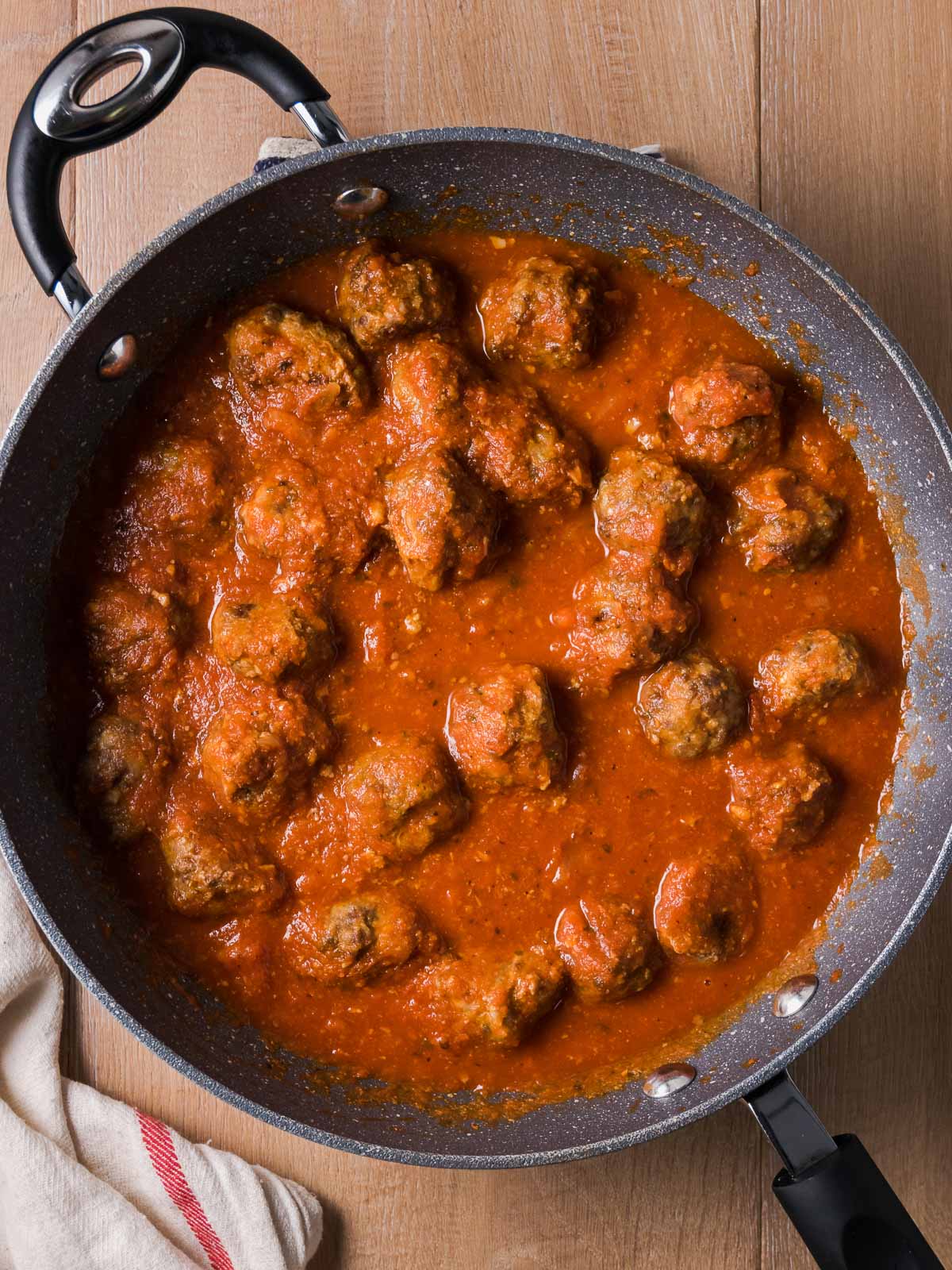 Gluten Free Meatballs simmer in a skillet with tomato sauce.