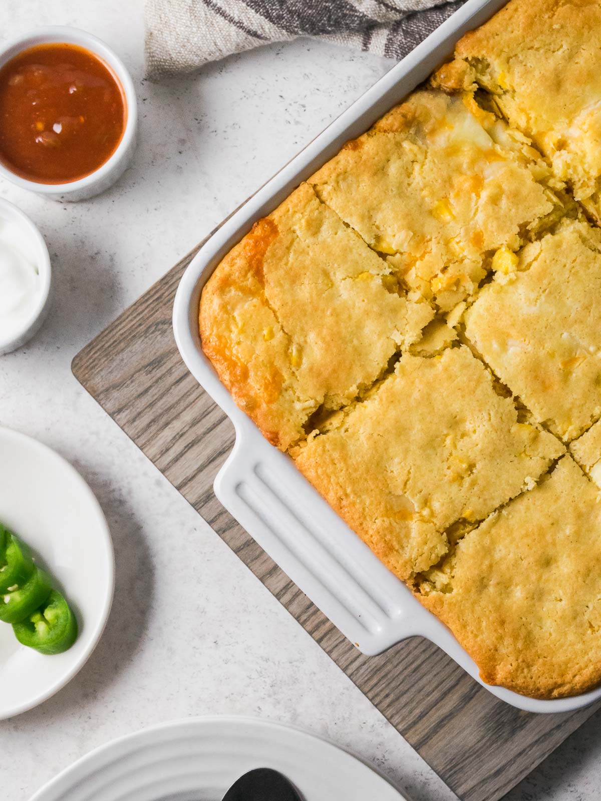 A dish of Mexican cornbread casserole cut into slices and ready to serve.