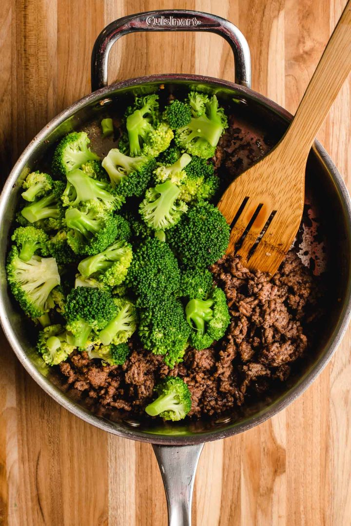 Ground beef and broccoli in a stainless steel skillet.