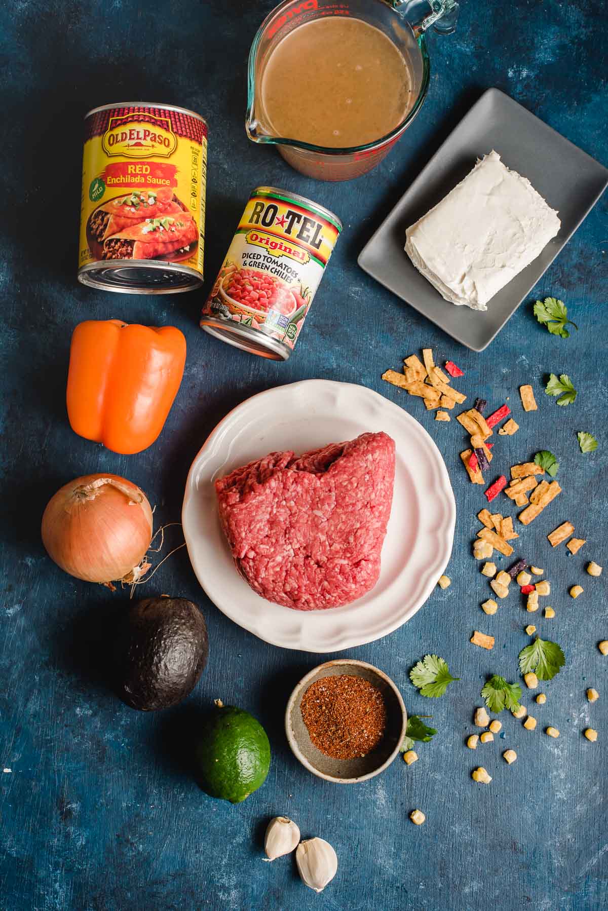 Ingredients for enchilada soup arranged on a deep blue background.