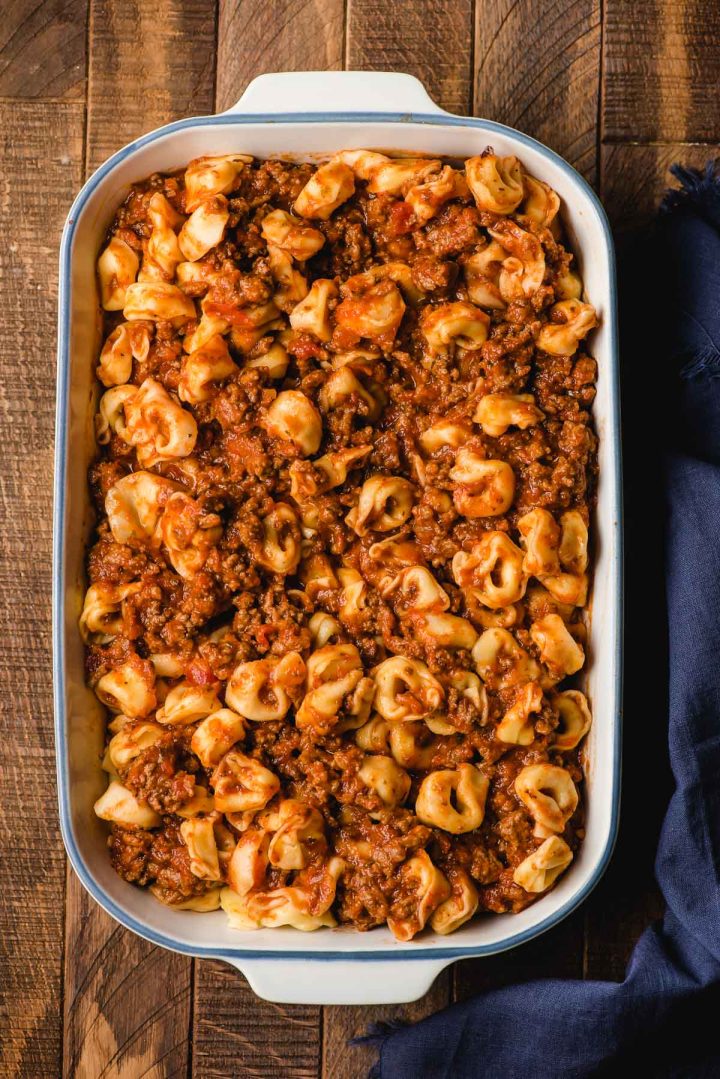 Tortellini tossed with tomato sauce and ground beef in a casserole dish.