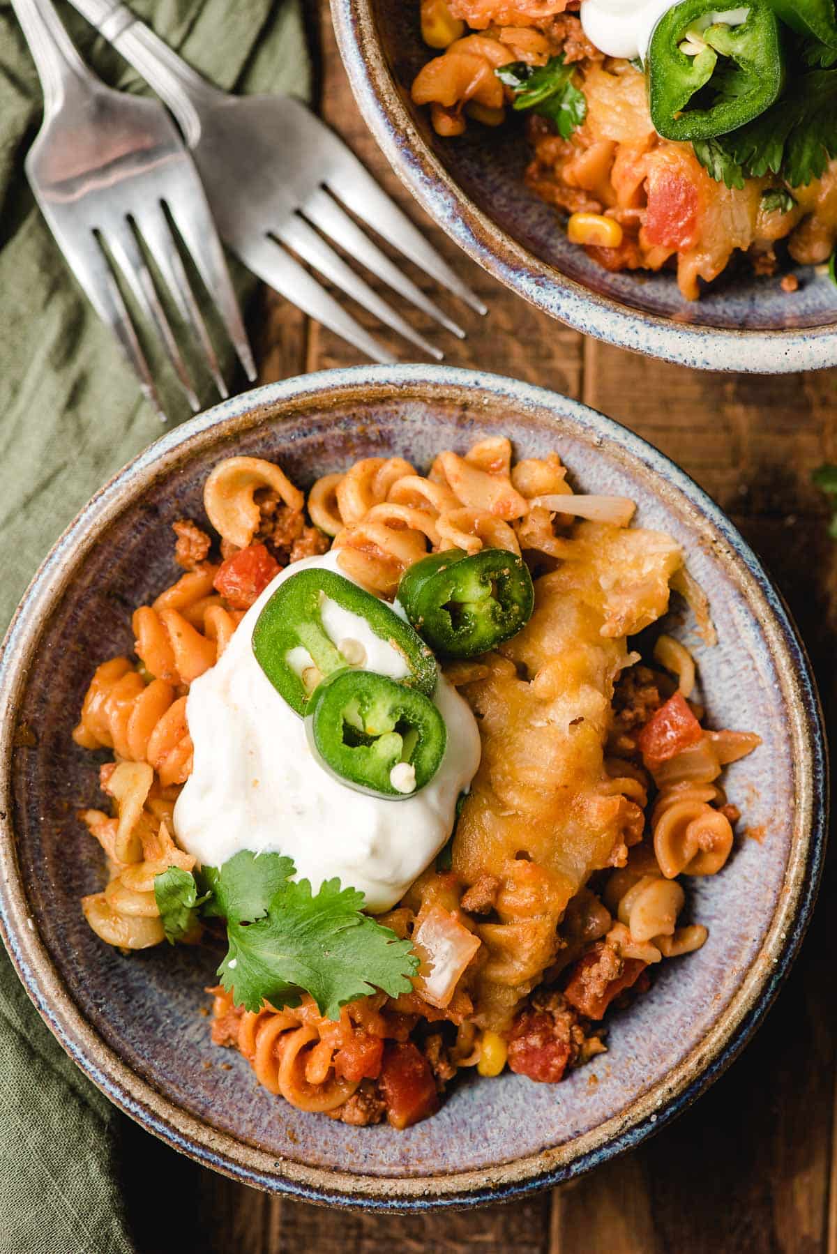 A bowl of Taco Pasta Casserole topped with sour cream, jalapenos and cilantro.