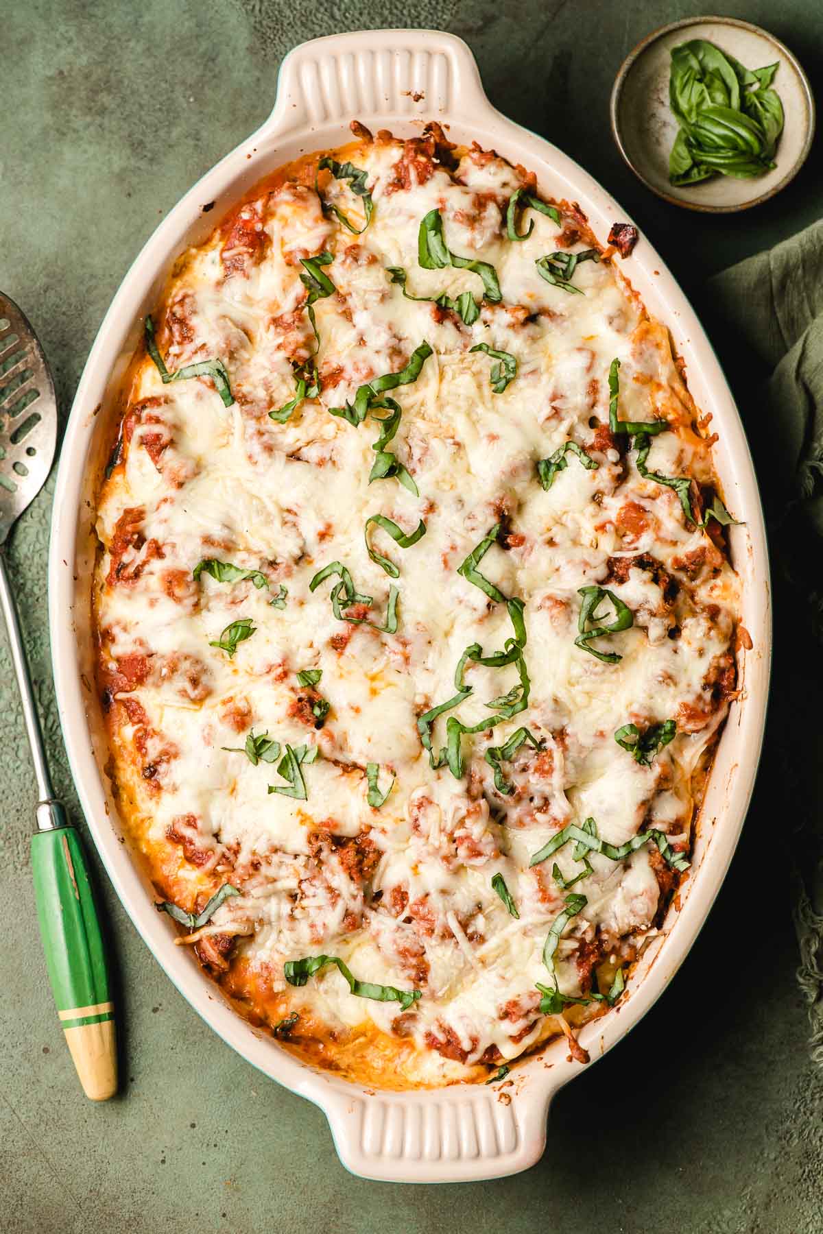 A serving dish full of Stuffed Shells with Ground Beef topped with cheese and basil.