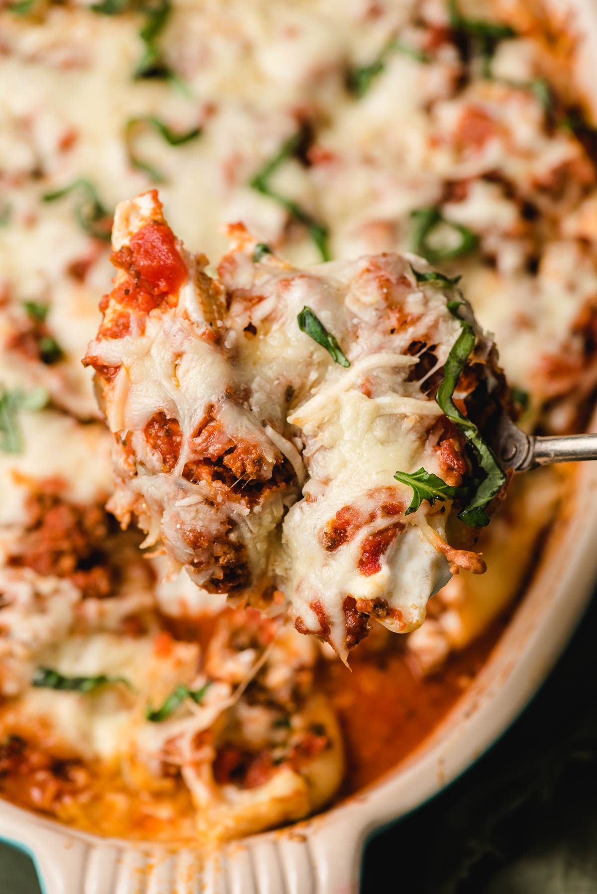 Fresh basil and baked cheese top a dish of stuffed shells with ground beef.