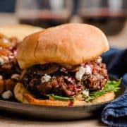 Goat cheese burgers on a plate, topped with caramelized onions and a red wine glaze.