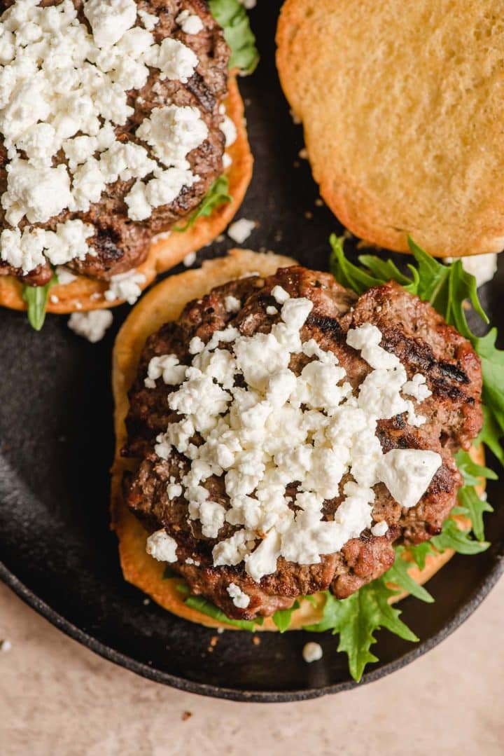 Goat cheese on top of a burger on a bun.