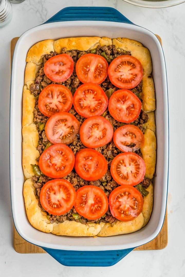 Tomato slices on top of a hamburger and biscuit casserole.