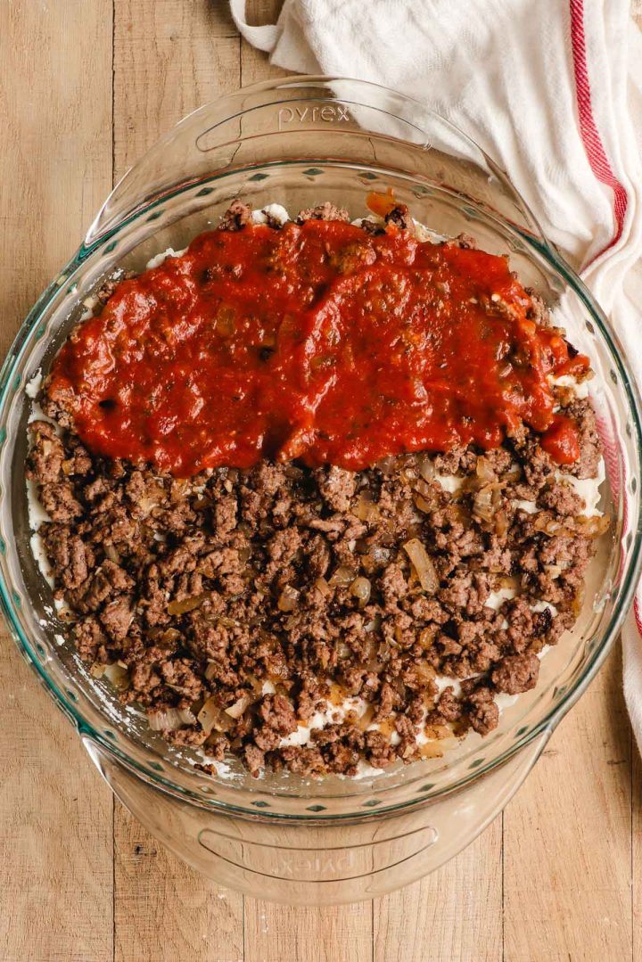 Ground beef and marinara sauce spread over ricotta cheese in a casserole dish.
