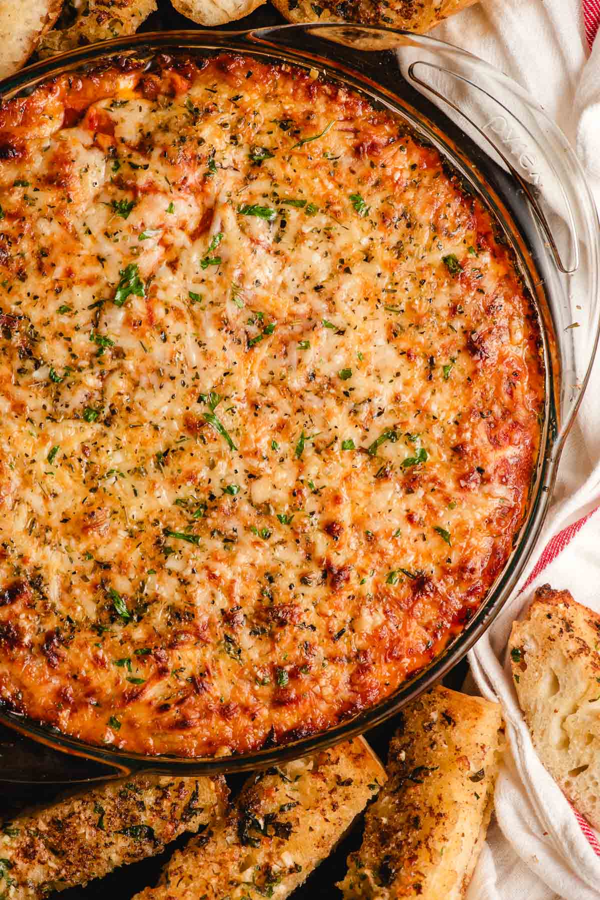Ultra cheesy baked lasagna dip surrounded by garlic bread dippers.