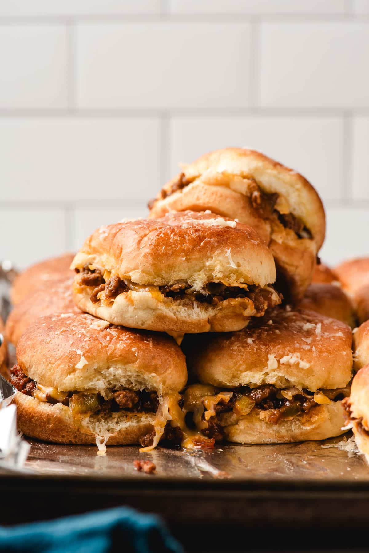 A stack of sloppy joe sliders on a baking tray.