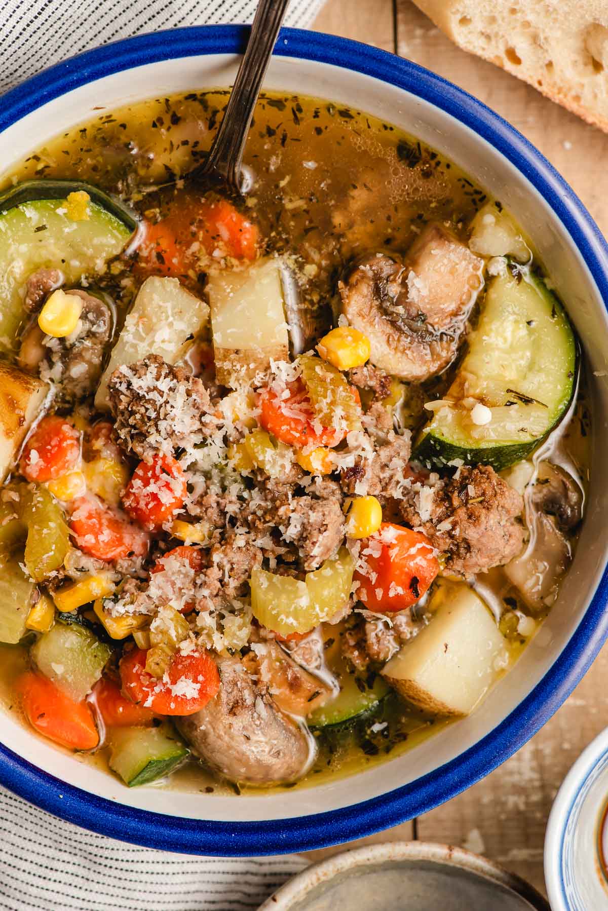 Bowl of vegetable soup with ground beef, sprinkled with Parmesan cheese.