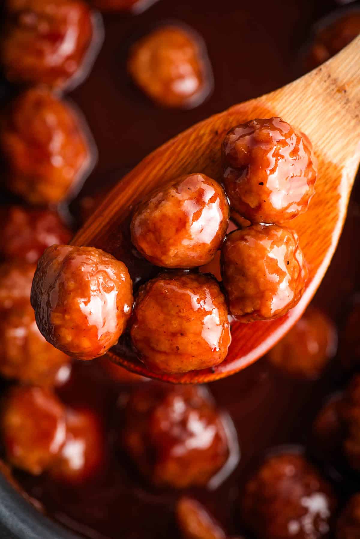 Wooden spoon with BBQ grape jelly meatballs on ti.