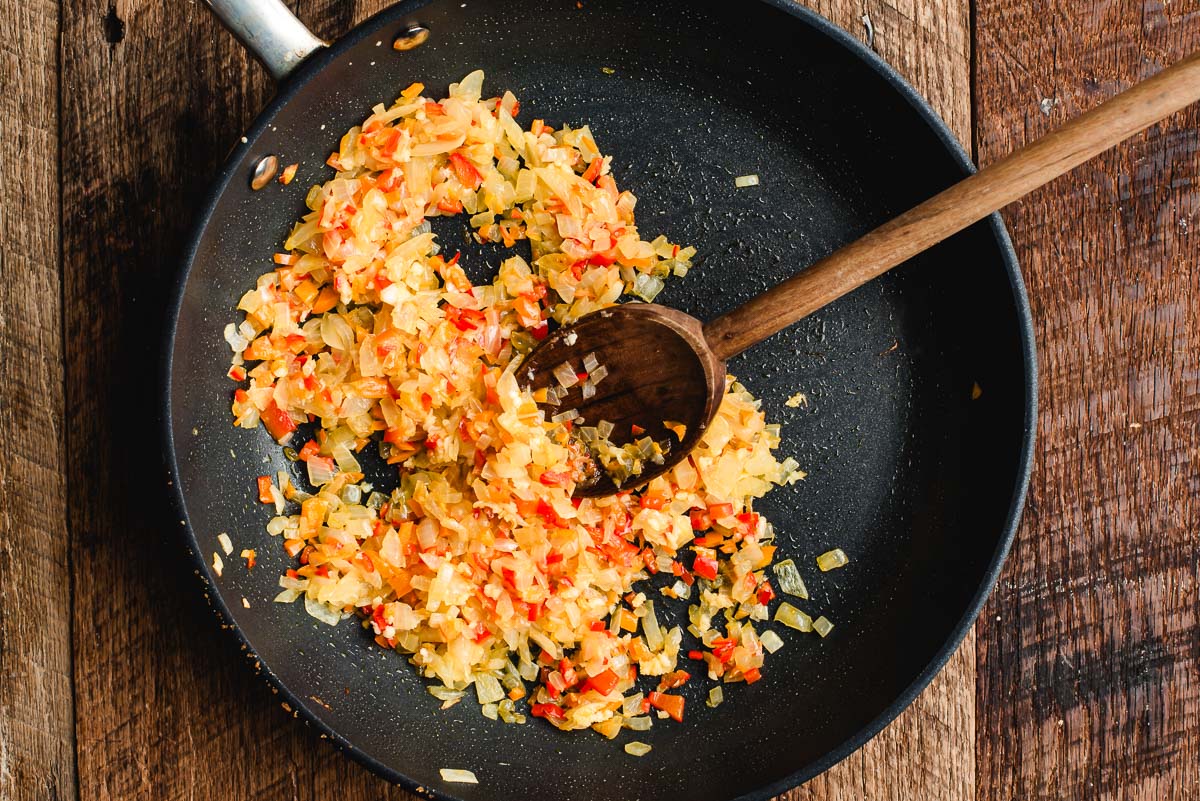 Sauteed diced red bell pepper and onion in a skillet.