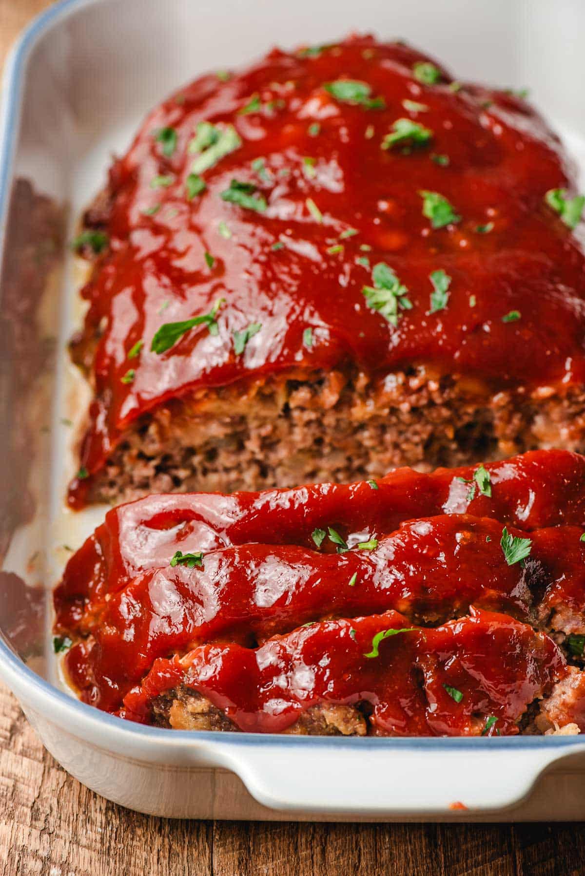 Slices of meatloaf in a white casserole dish.