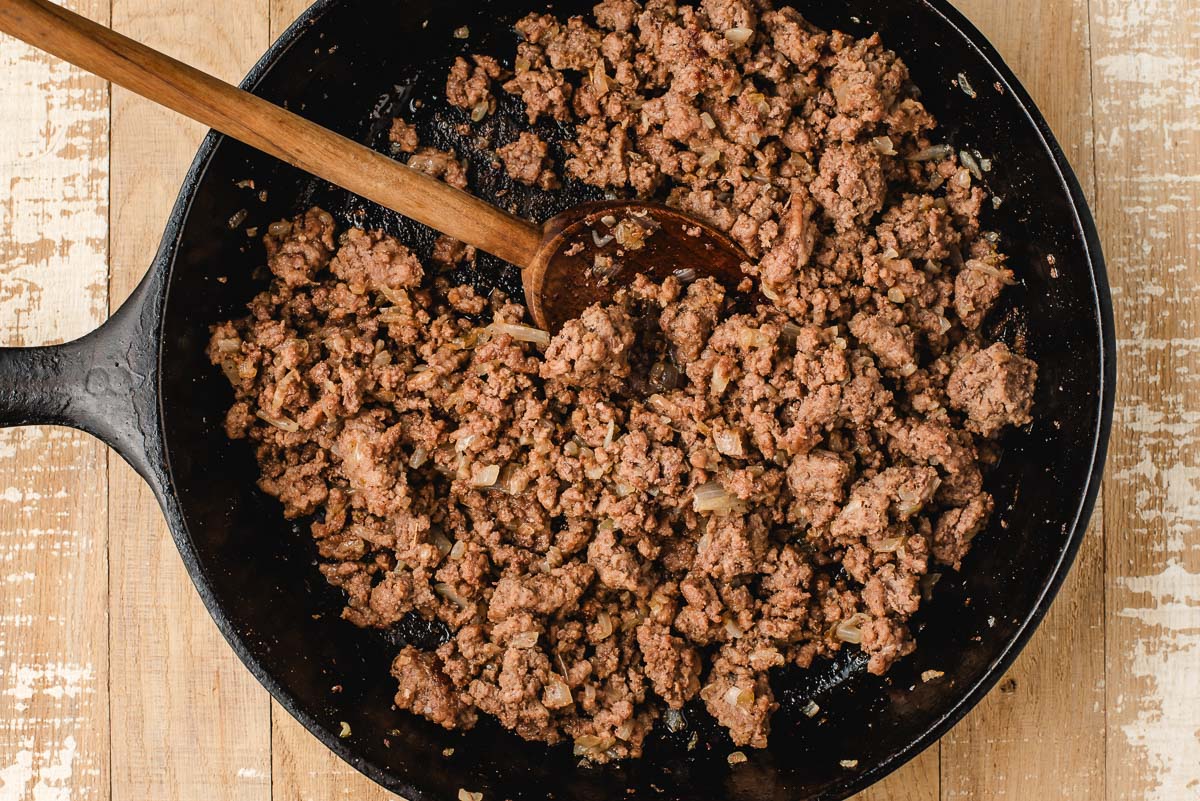 Ground beef and onions sauteed in a cast iron skillet.