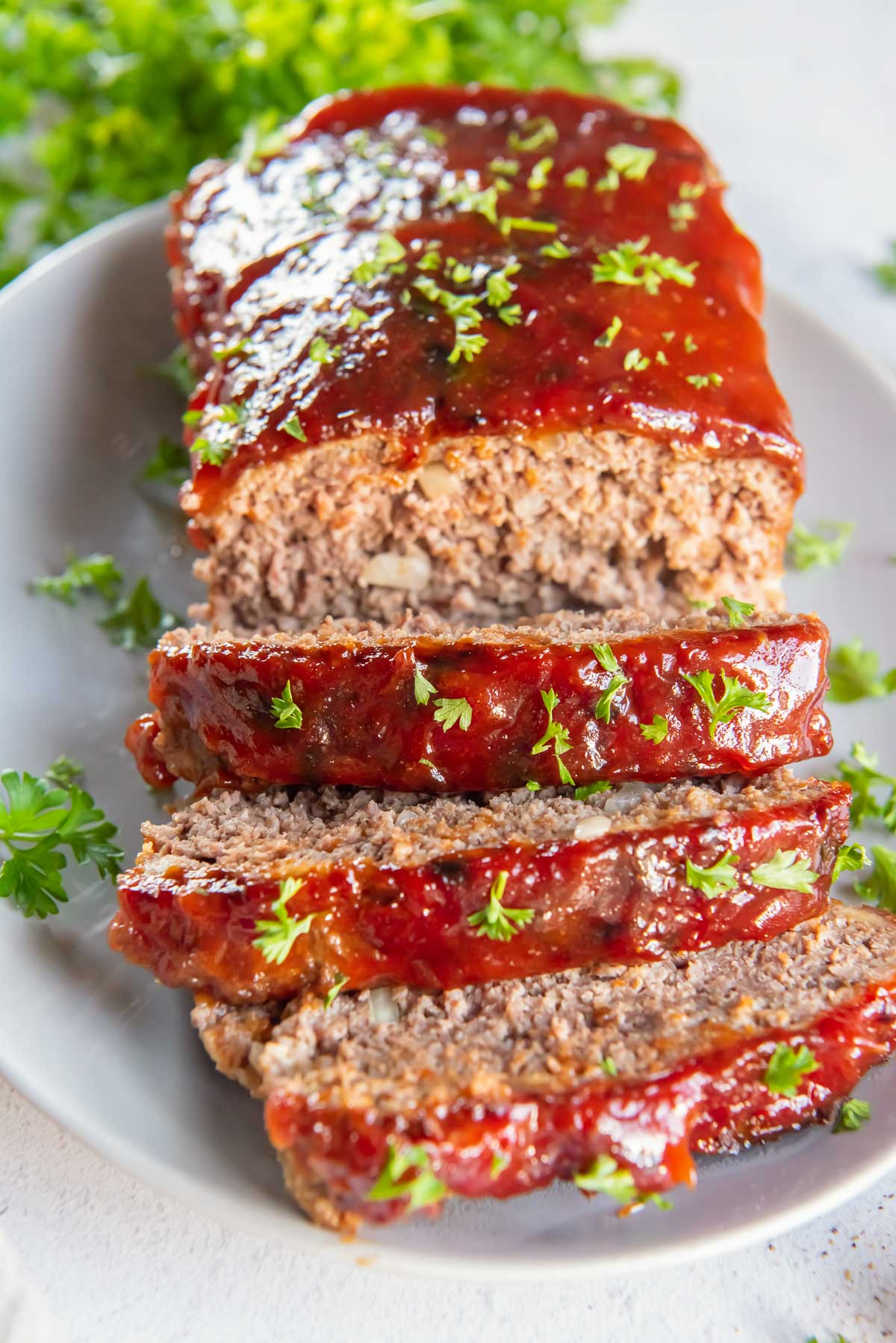 A sliced air fryer meatloaf topped with ketchup glaze and parsley.