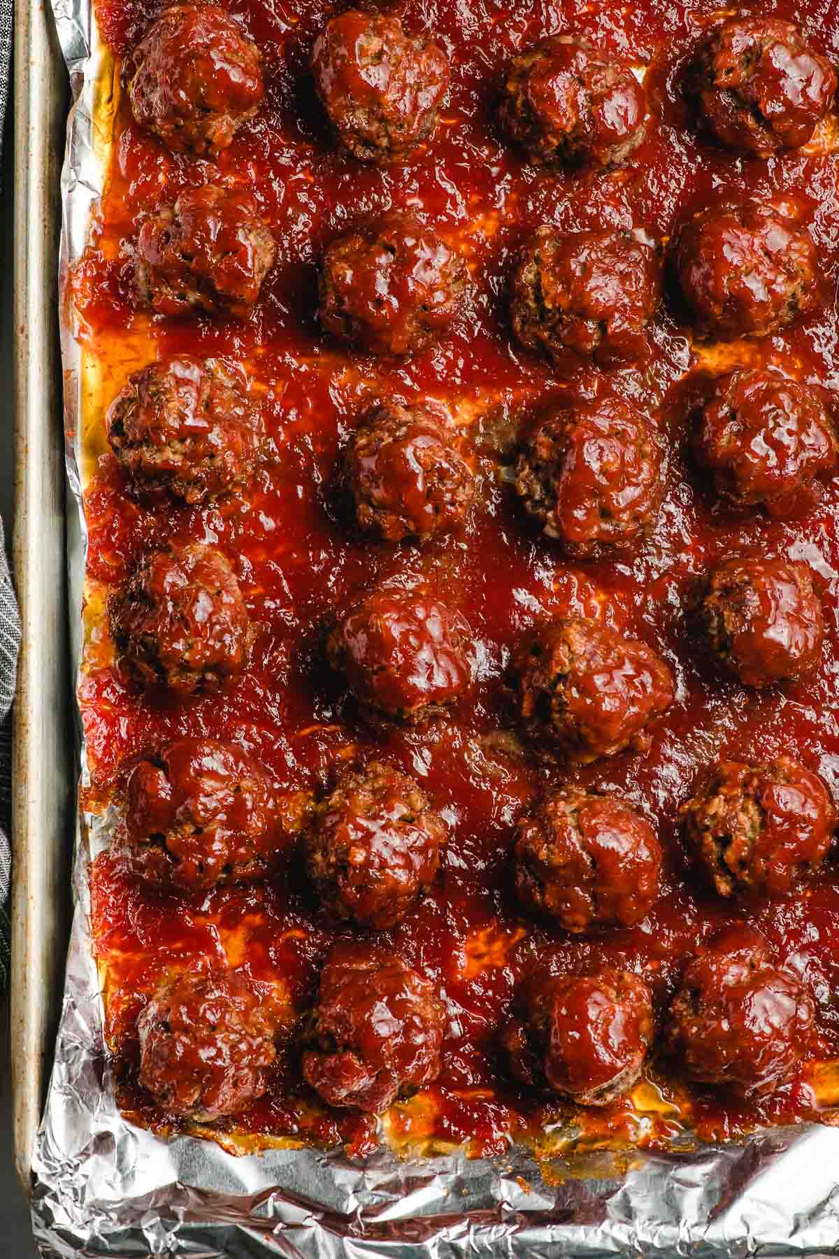 Oven baked bbq meatballs on a foil lined baking sheet.