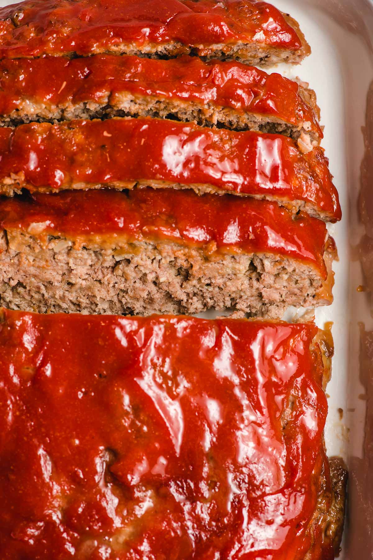 Easy meatloaf recipe shown baked and sliced in a casserole dish.