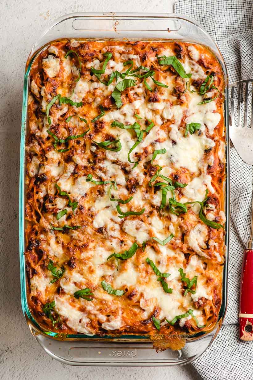 Baked spaghetti in a casserole dish with melted cheese on top.