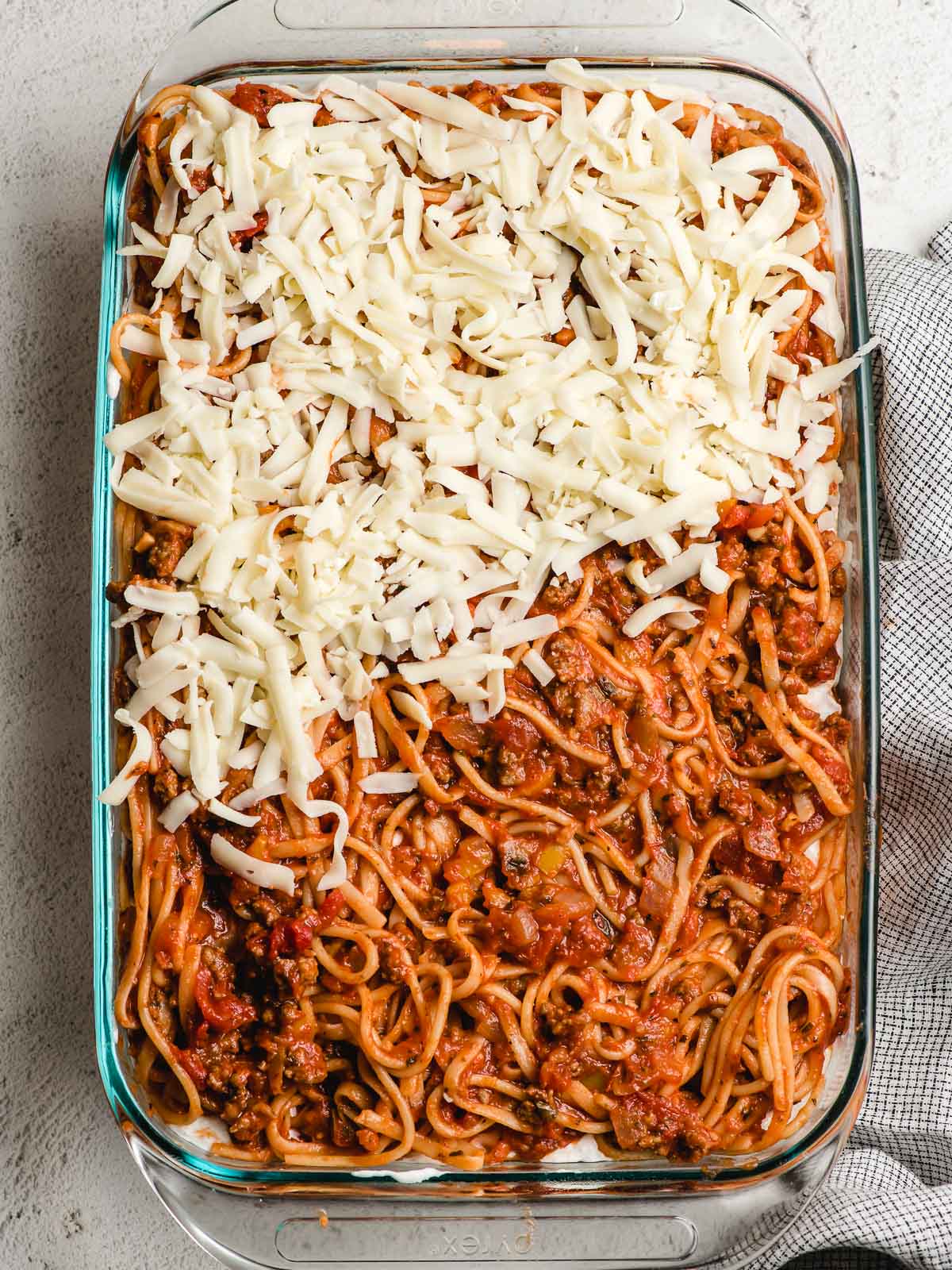 Glass casserole dish full of spaghetti, cottage cheese, and cheese.