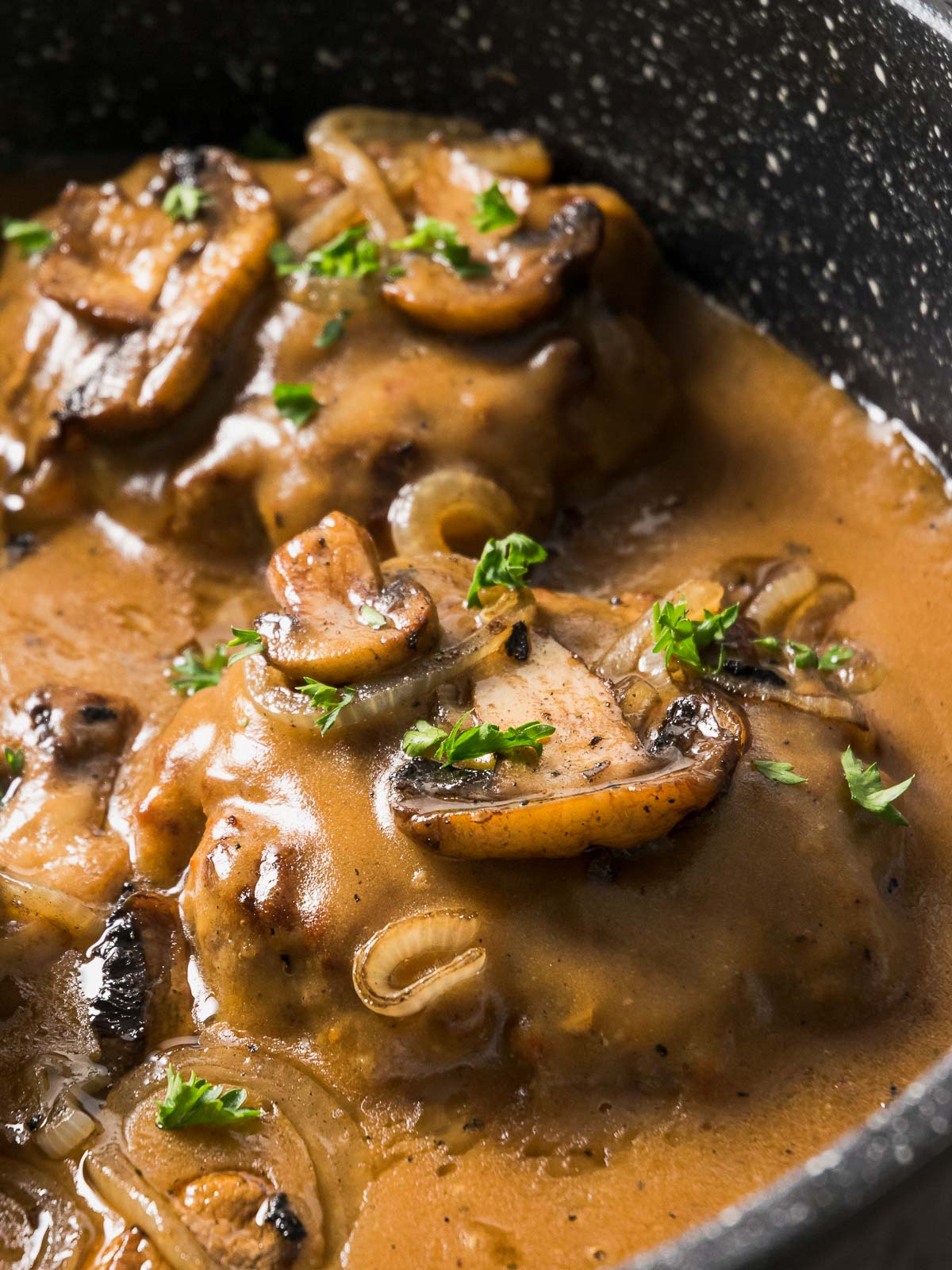Smothered Hamburger Steak and Gravy simmers in a skillet.