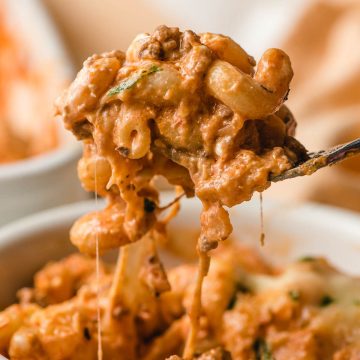 A fork lifts a cheesy bite of ground beef pasta casserole.