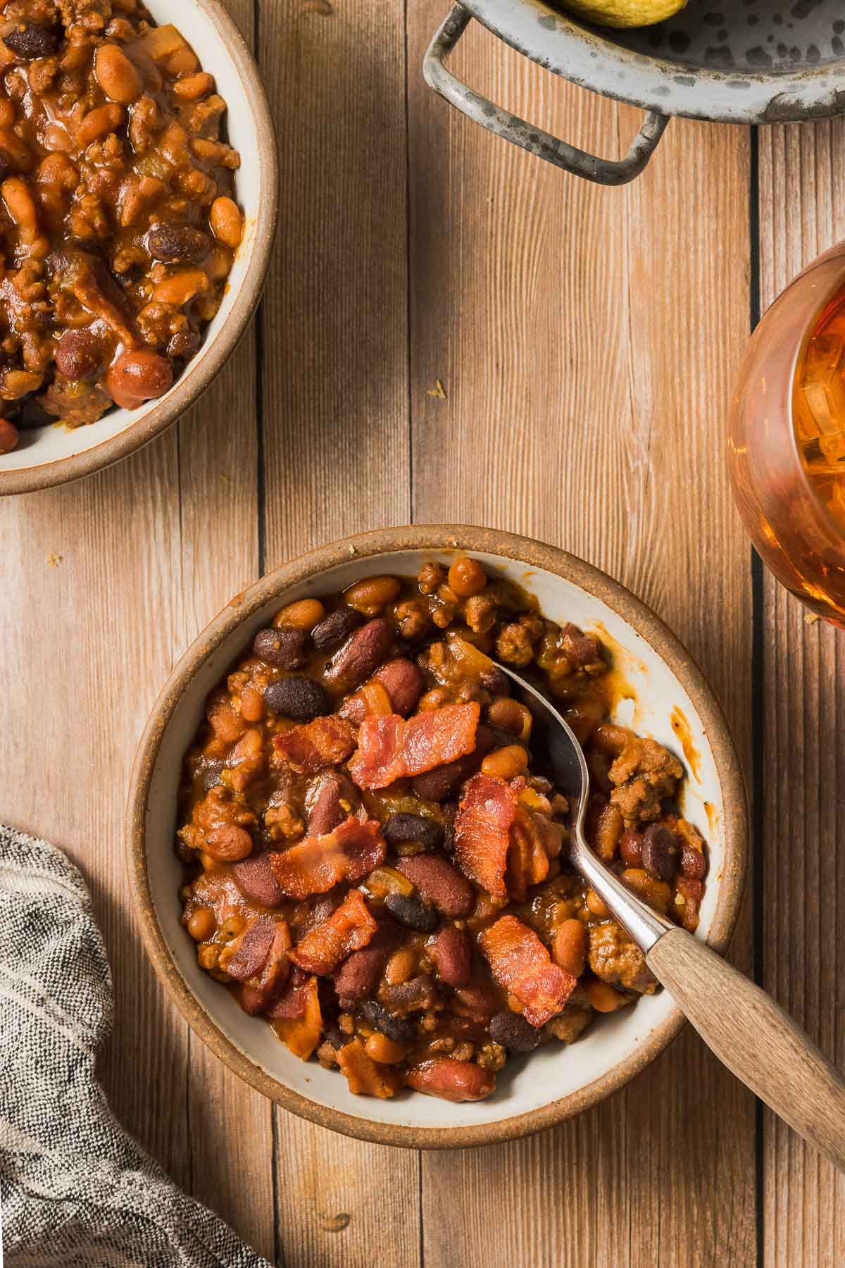A table set with a few bowls of cowboy baked beans with ground beef.