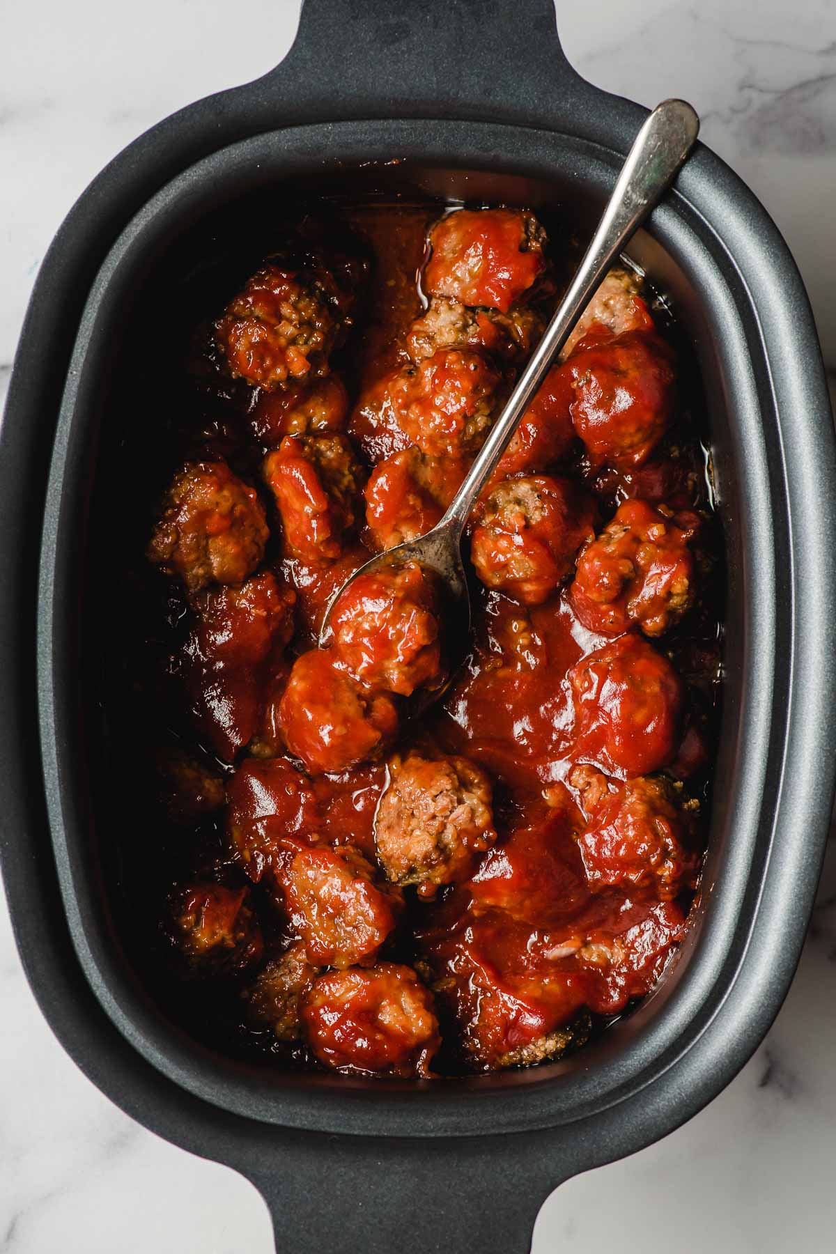 Crock Pot BBQ Meatballs with a spoon scooping a few meatballs out of the crock.