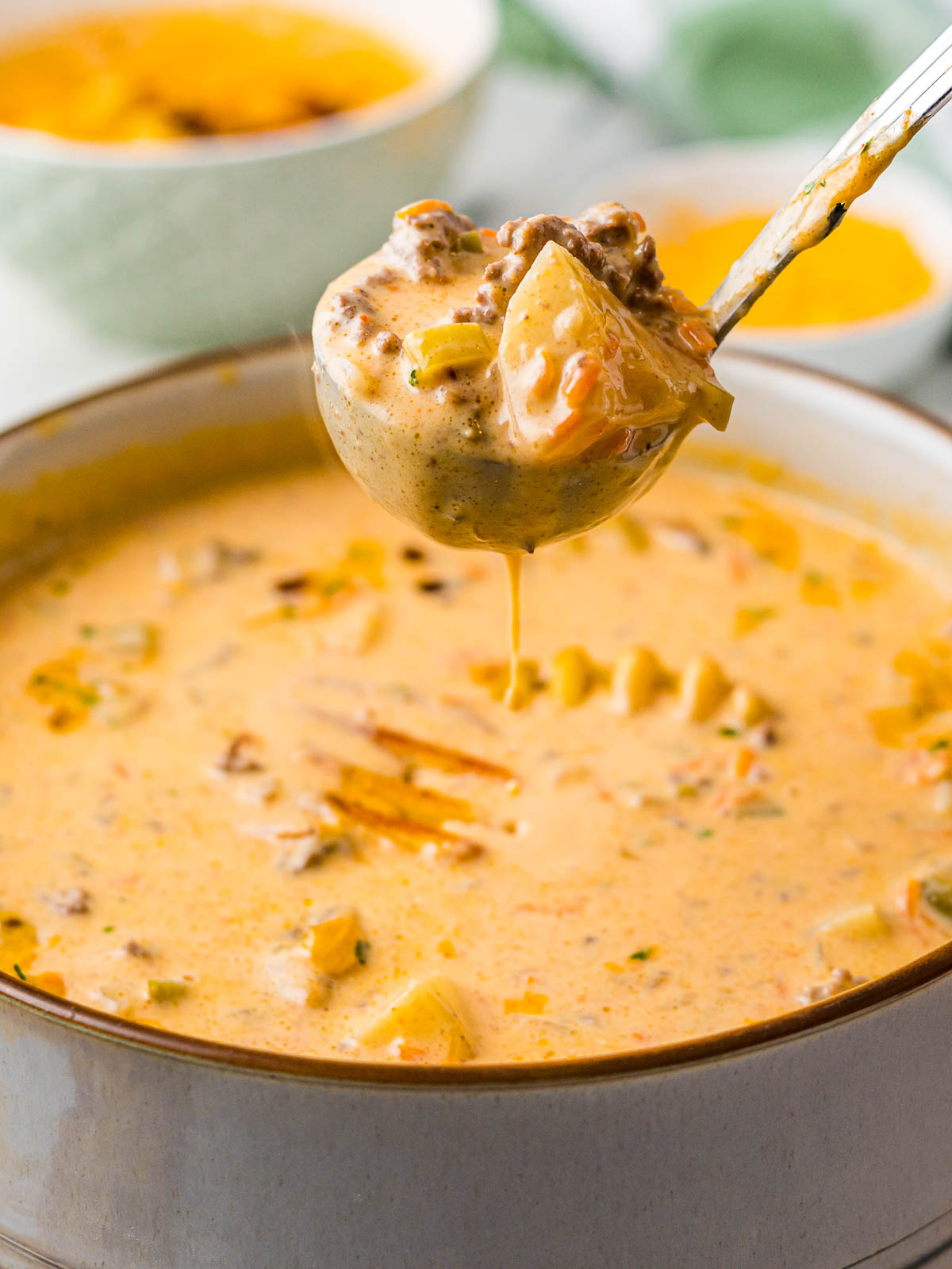A spoon gets a scoop of Crock Pot Cheeseburger Soup from a bowl.