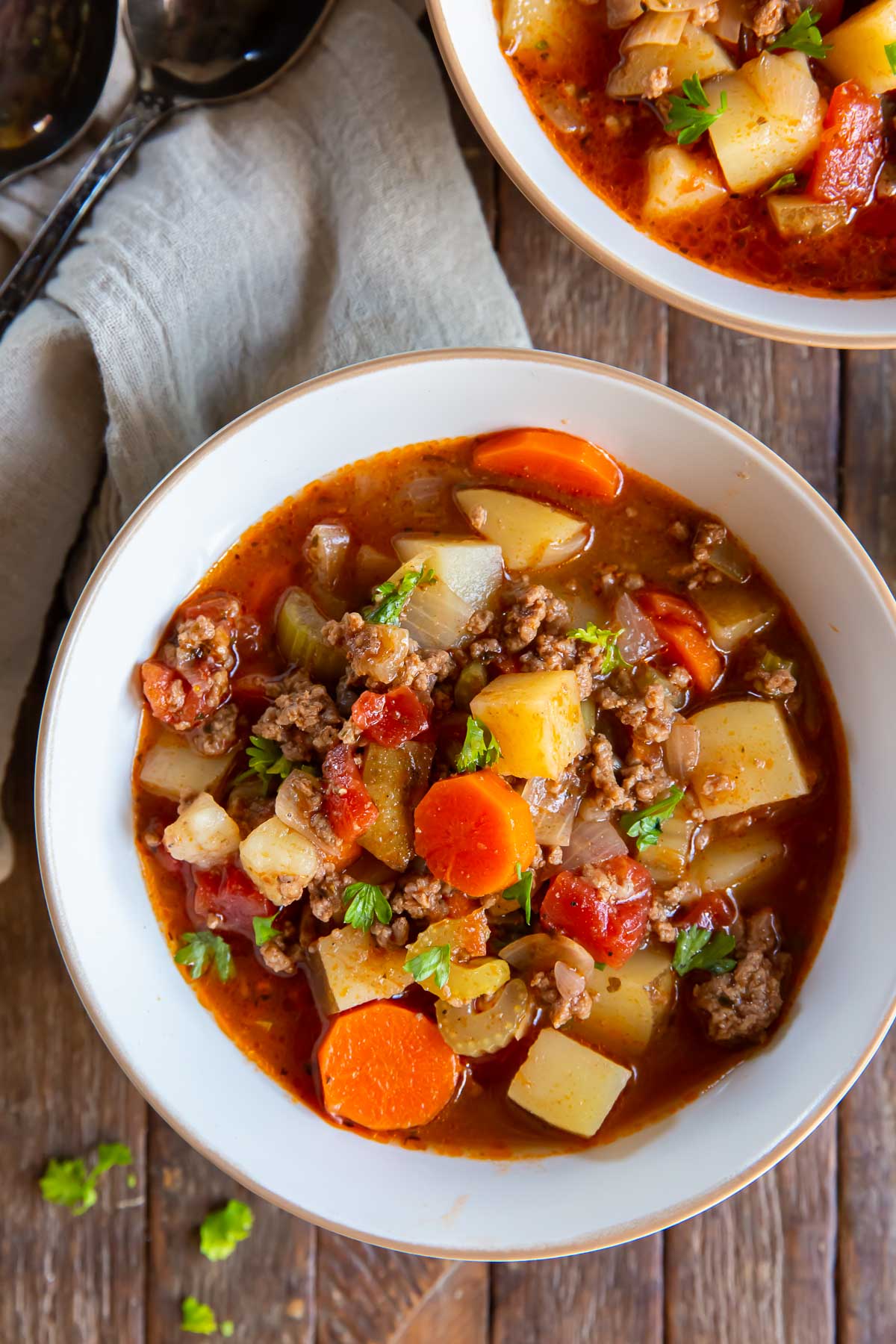 Slow Cooker Hamburger Soup with potatoes, carrots, celery, and onions shown in a white bowl.