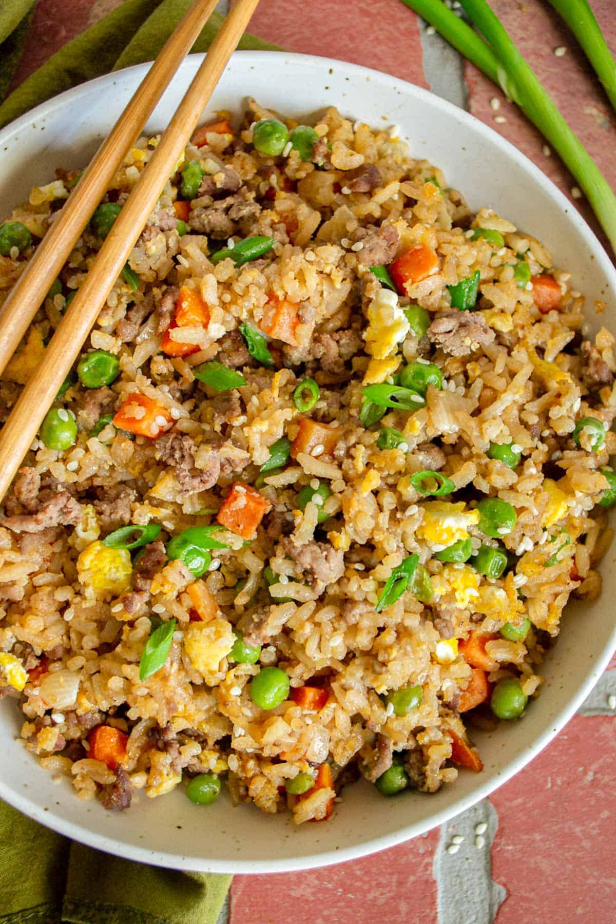 Bowl of ground beef fried rice on a brick background.