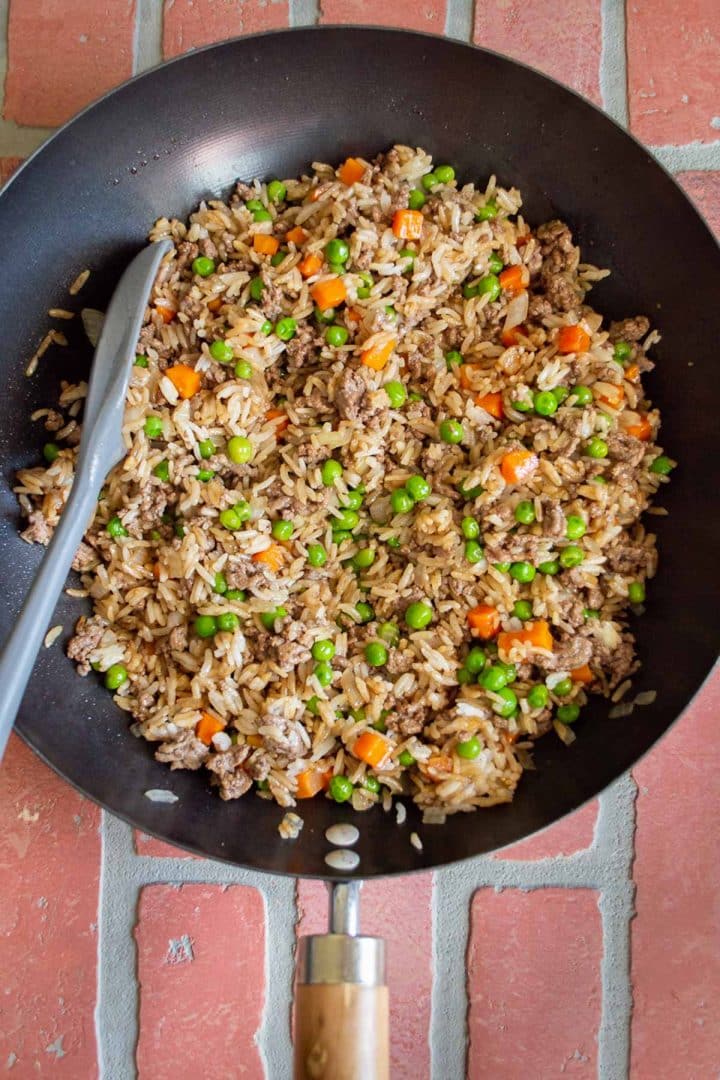 Ground beef and rice in a skillet with veggies and soy sauce.