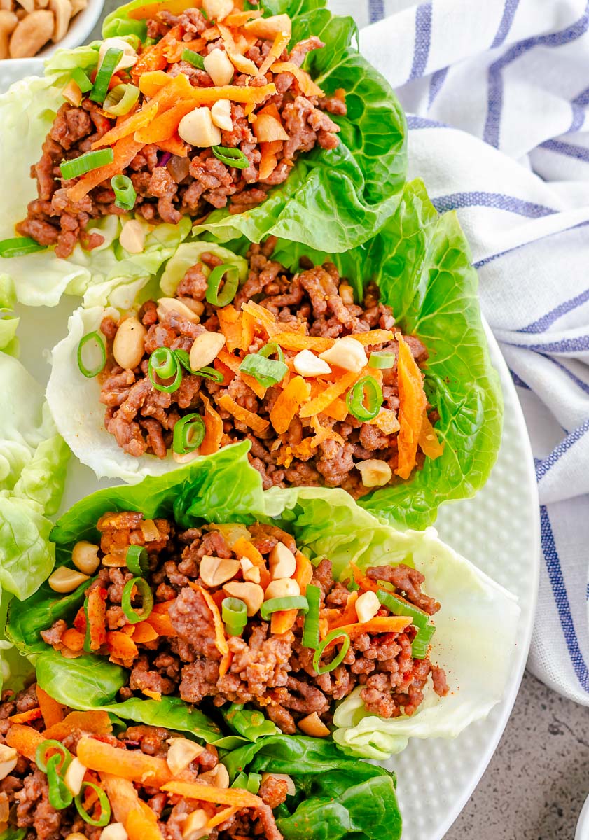 Row of ground beef lettuce wraps on a white plate.