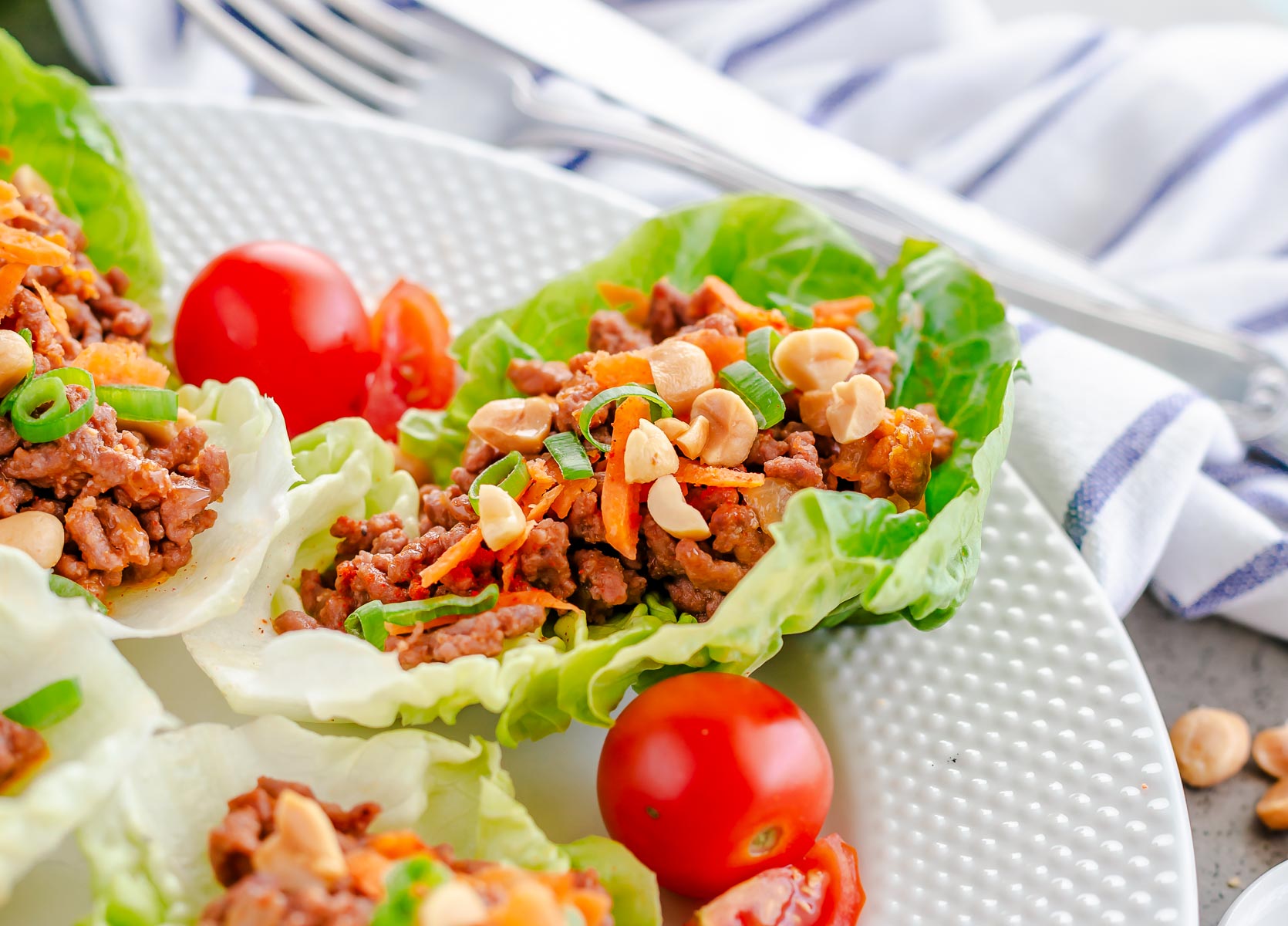 Close up image of a lettuce wrap topped with carrots and peanuts.