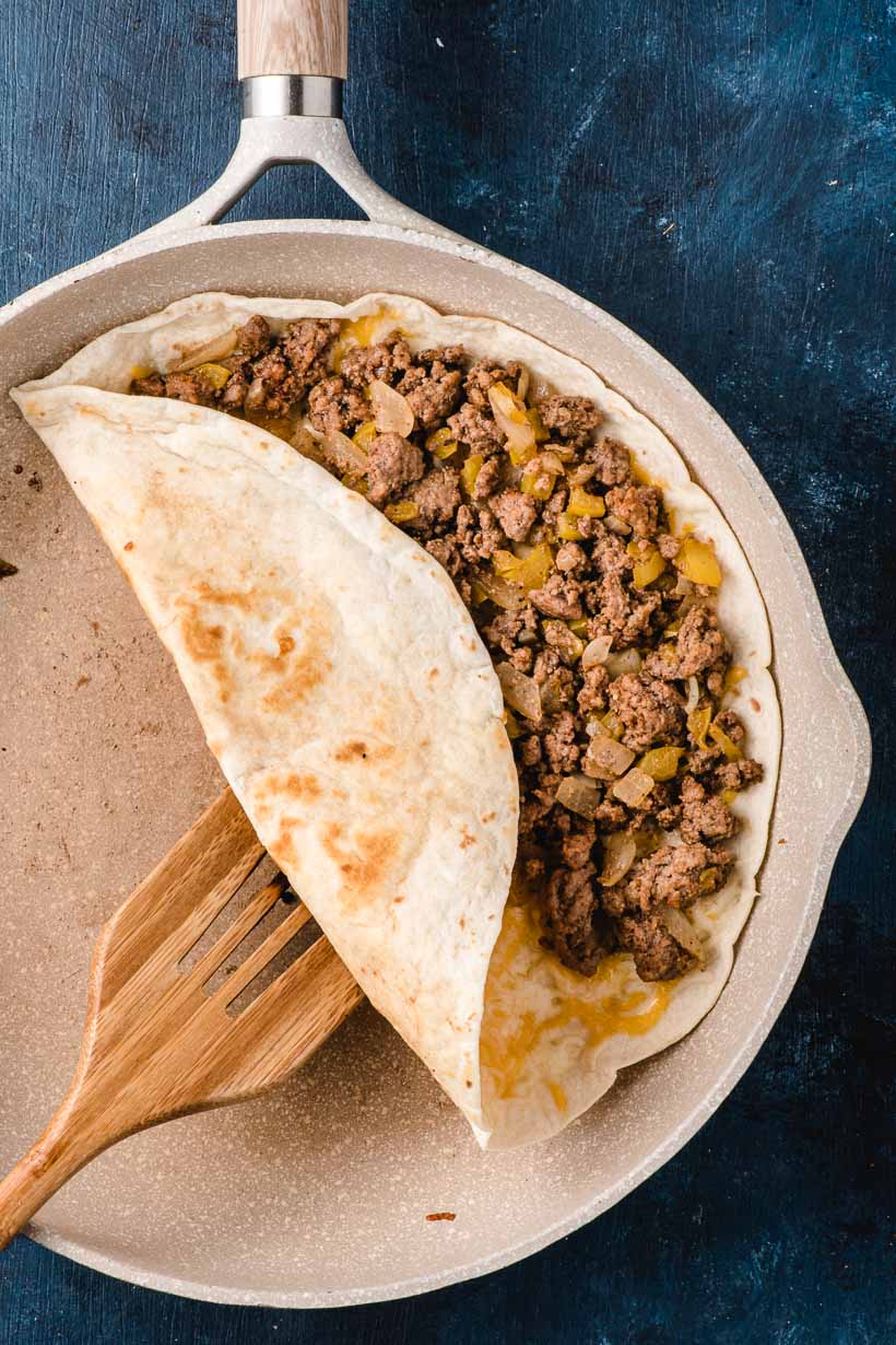 A spatula turns a Ground Beef Quesadilla in a skillet.