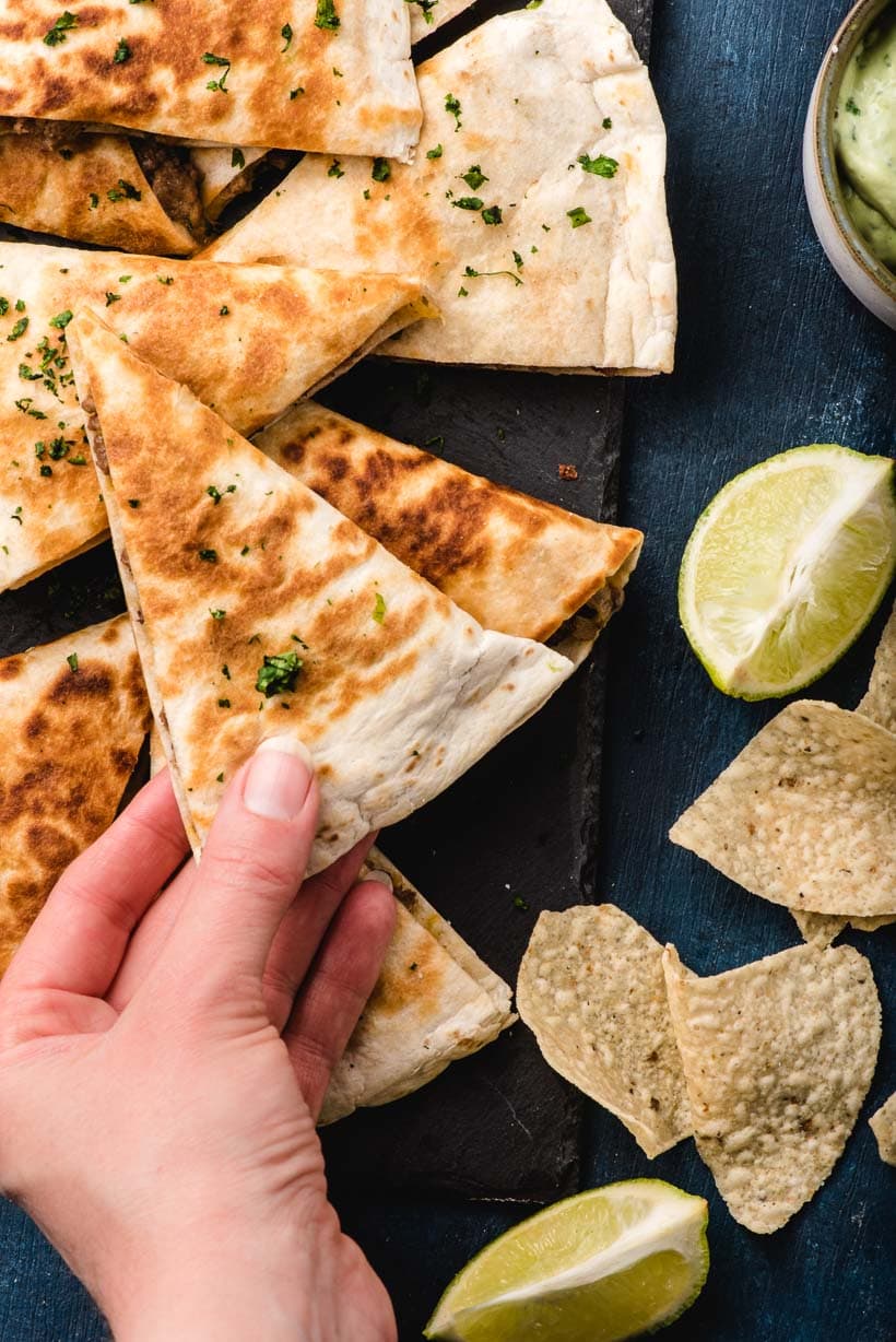 A hand takes a Ground Beef Quesadilla off a snack platter.