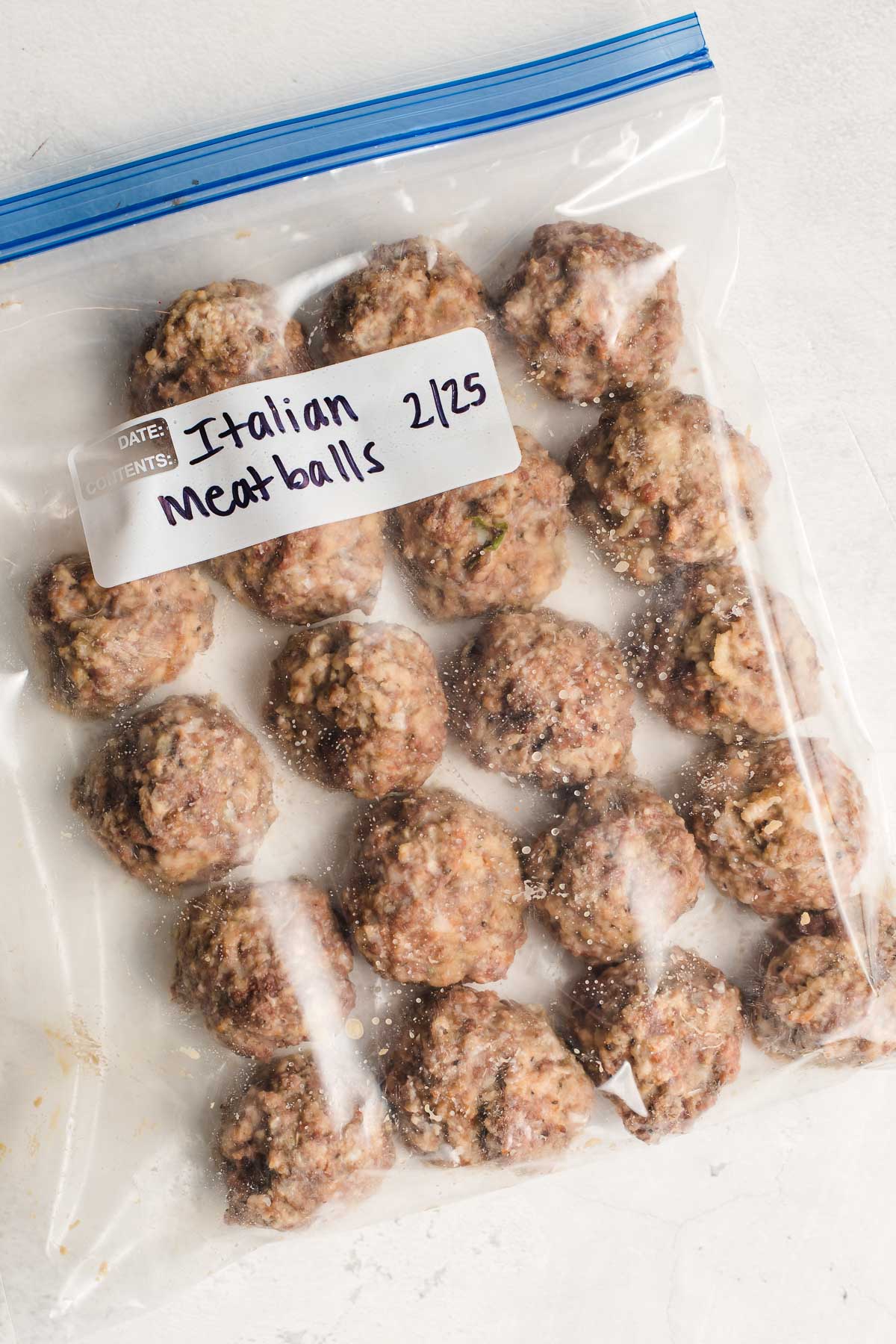 Italian meatballs shown in a ziplock bag, labeled for freezing.