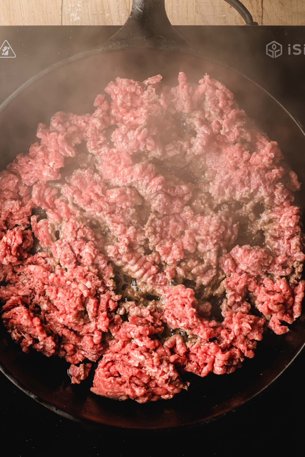 Ground beef cooking in a cast iron skillet.