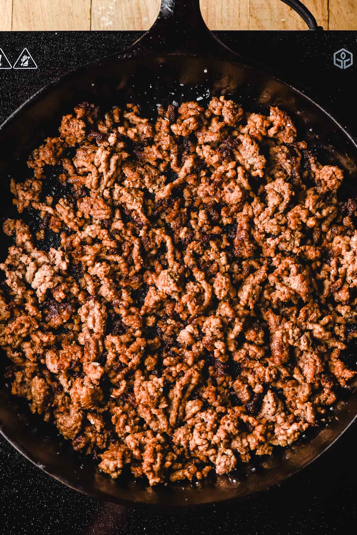 Cooked ground beef with crispy browned bits in a cast iron skillet.