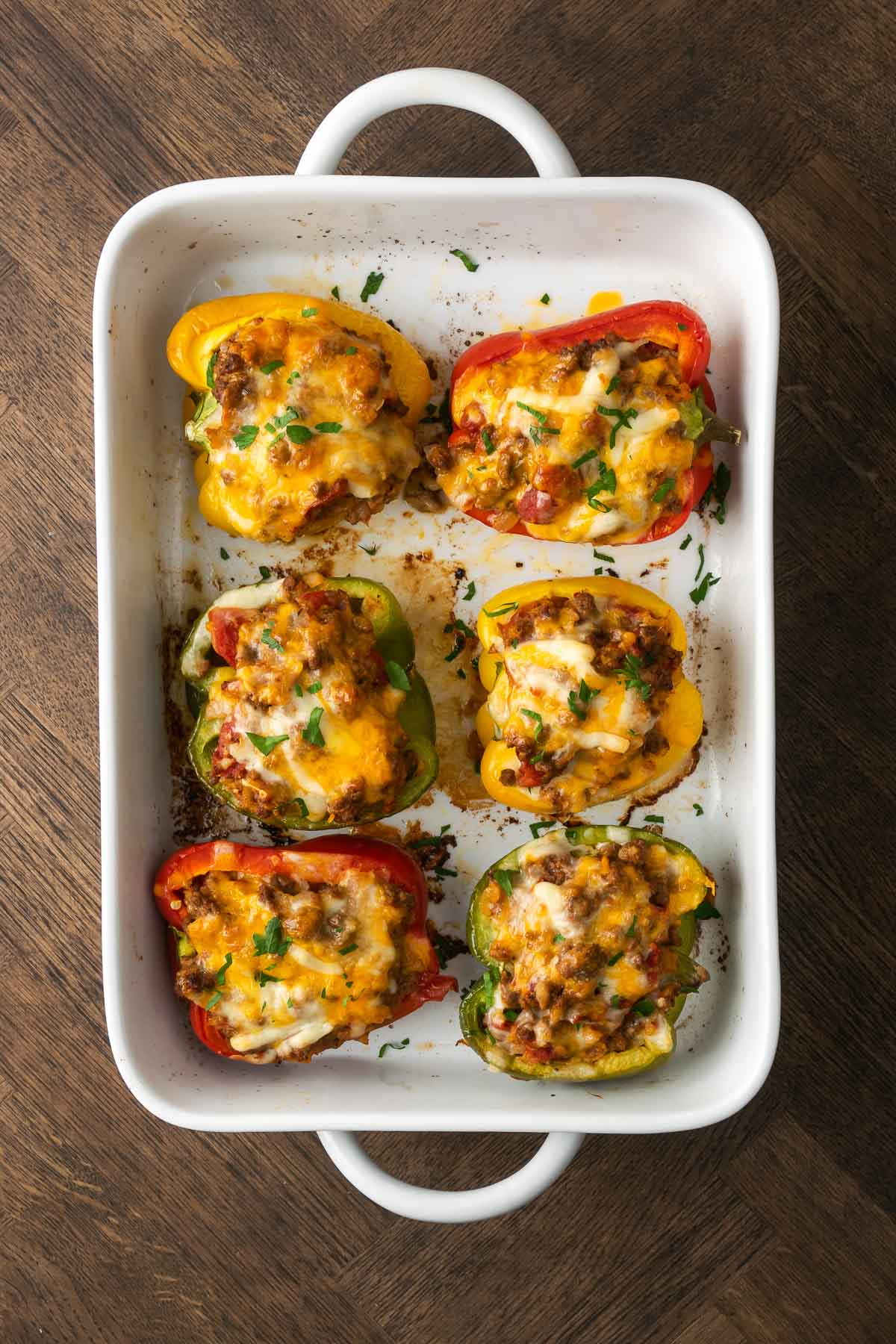 Baking dish full of Keto Stuffed Peppers topped with cheese.