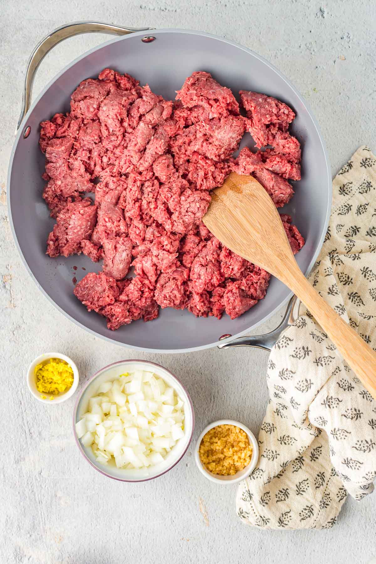 Skillet full of raw ground beef about to be cooked.