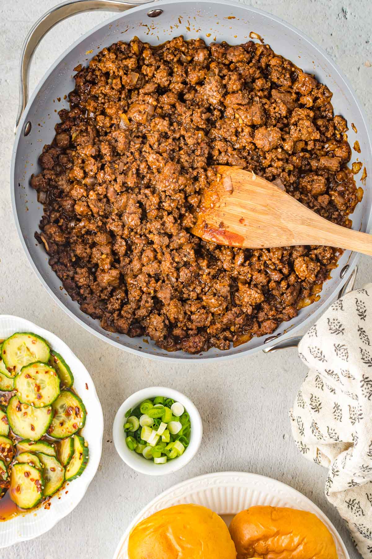Skillet filled with sloppy joes being stirred by a wooden spoon.