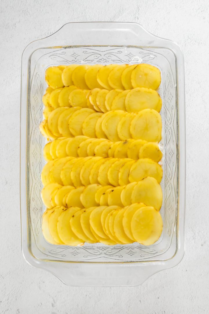 Sliced potatoes arranged like shingles in a casserole dish.