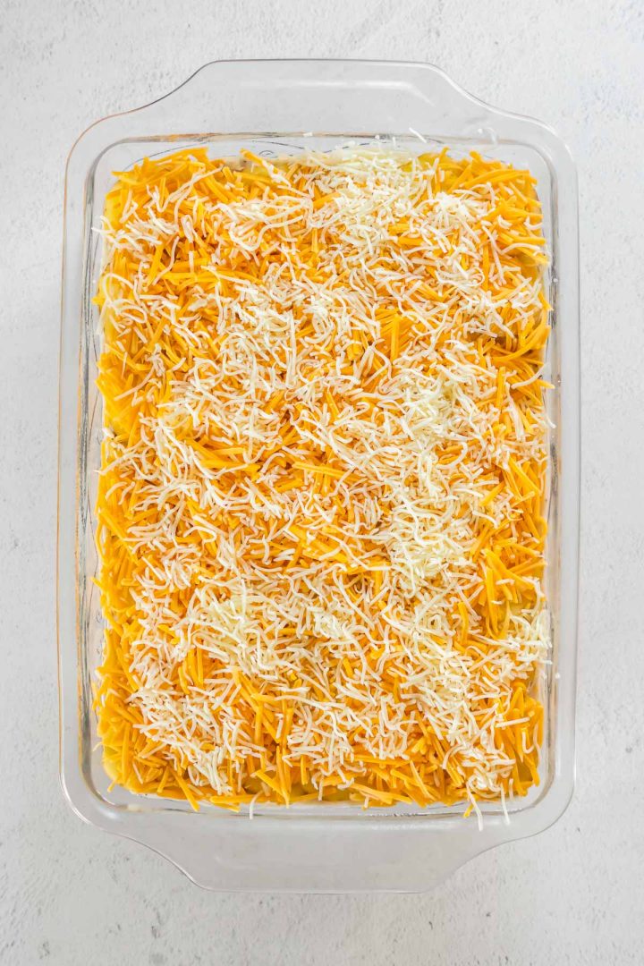 Unbaked casserole topped with shredded cheddar and monterey jack cheese.