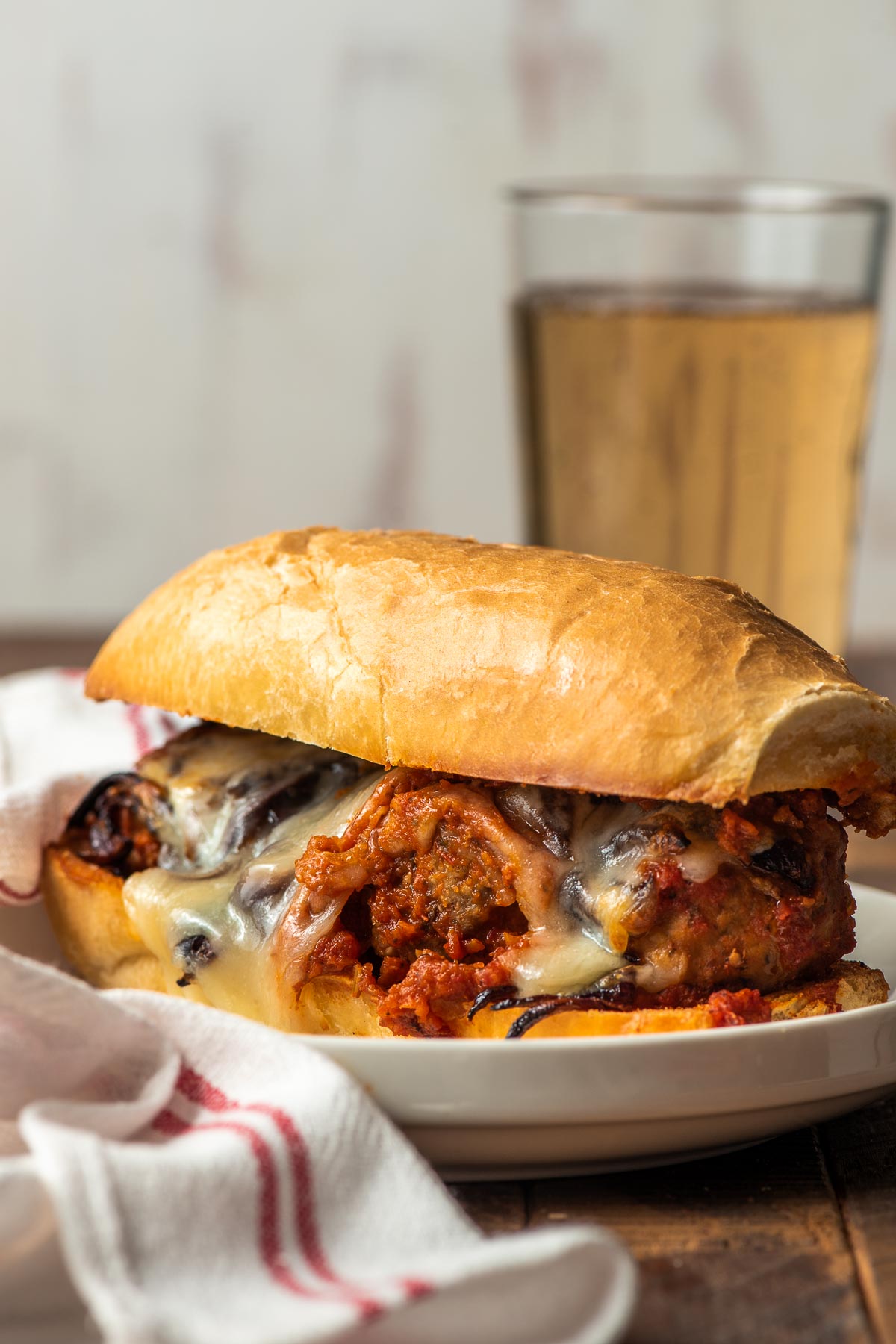 A saucy meatball sub served with a beer.