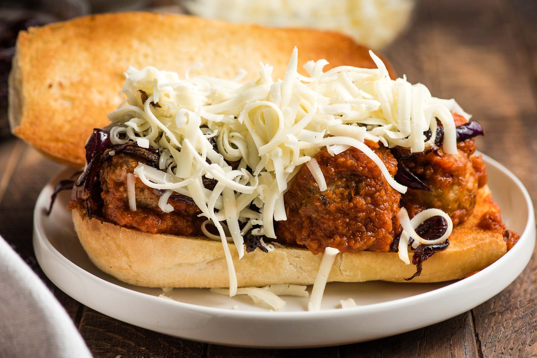Assembling a meatball sub on a plate.