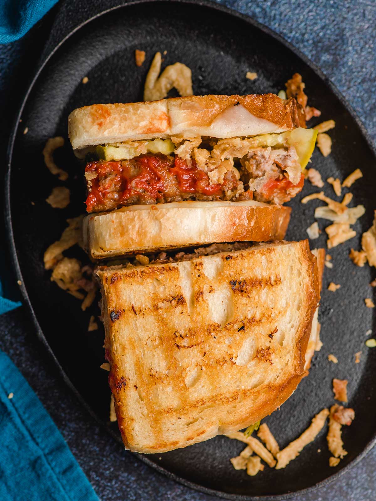 A toasty grilled hot meatloaf sandwich on a plate with crispy onions.
