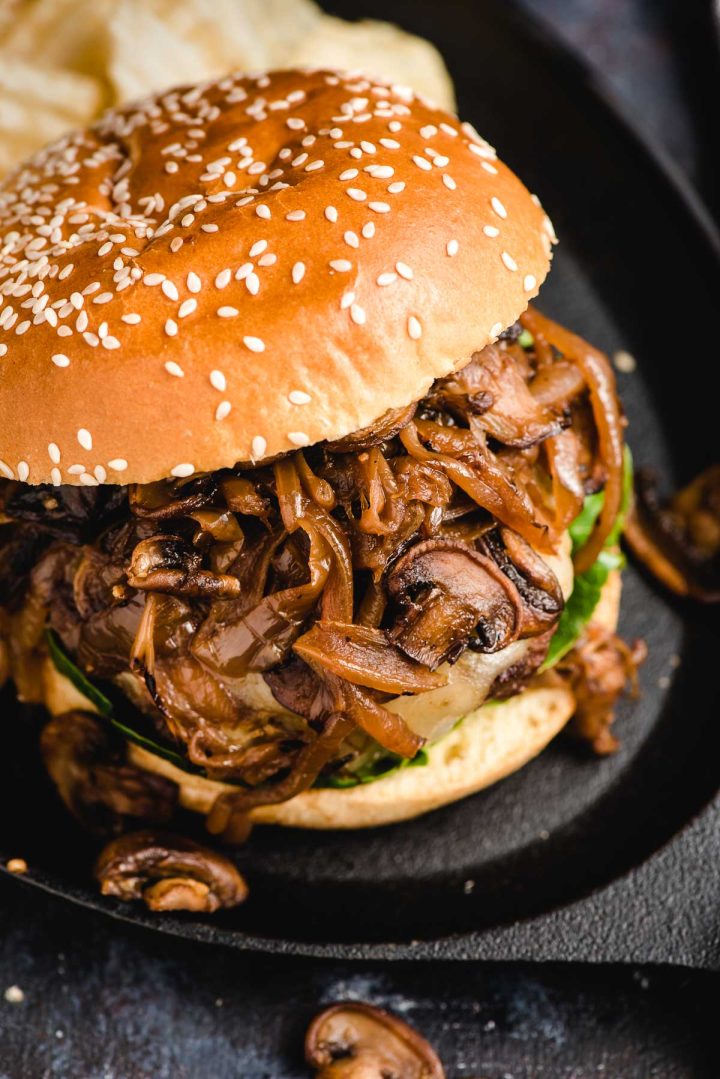 Top down image of a burger with caramelized onions and mushrooms on top.